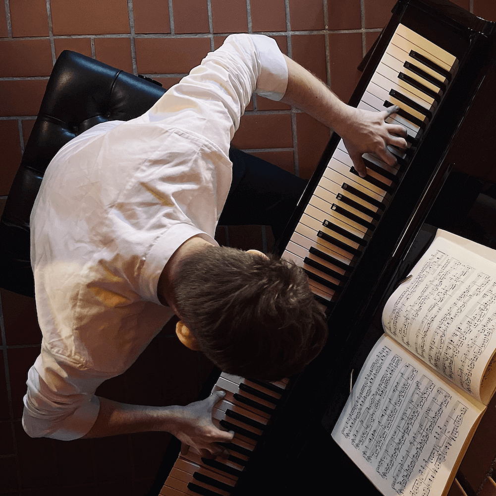 Tom Stephan am Klavier, Perspektive von oben. Sicht von oben auf das Klavier. Pianist spielt verdeckt klavier. Musiker am Instrument